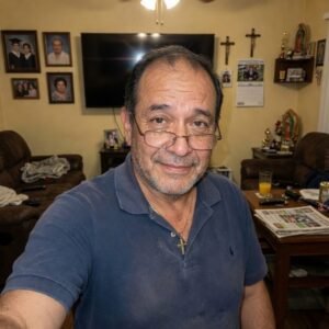 Hombre maduro con lentes y cabello oscuro sonriendo mientras se toma una selfie en sala de estar