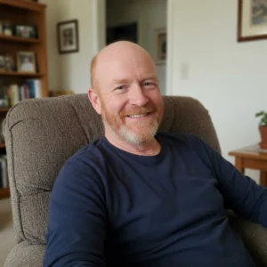 Hombre sonriente en un ambiente hogareño y relajado. Cliente que contrató al Estudio Sánchez Ferre para resolver un conflicto ambiental relacionado con contaminación Su expresión refleja la tranquilidad de haber encontrado solución legal a su problema ecológico.
